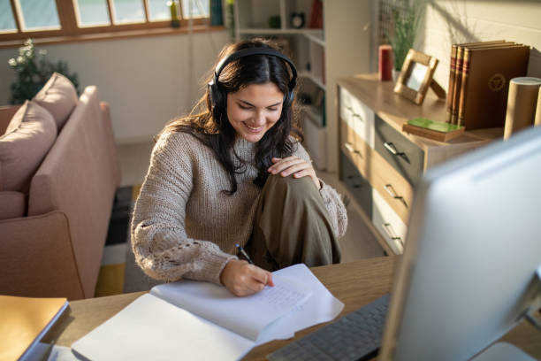 istock Teenage girl listening to music while using a computer for studying 1487270885