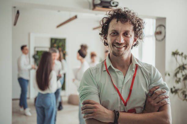 Portrait of a young creative man who is the leader of a team of people he is working with, they are in a relaxed work meeting and having a good time
