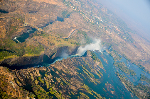 The Zambezi River in southern Africa has eroded the basalt and sandstone rock to form great chasms and cracks, as well as the largest sheet of falling water in the world, Victoria Falls waterfall. Shot from a helicopter flight in August 2013.