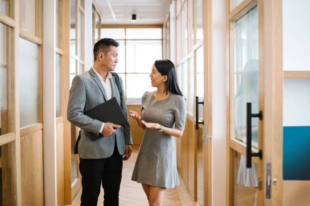 istock Two Asian Chinese businesspeople talking in corridor. 1487272288