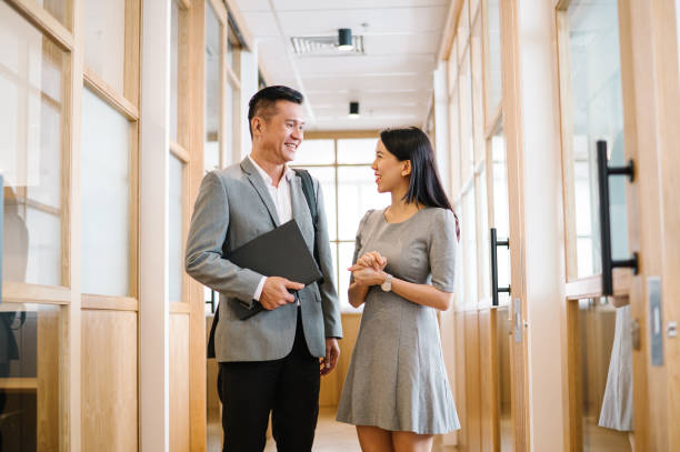istock Two Asian Chinese businesspeople talking in corridor. 1487272290