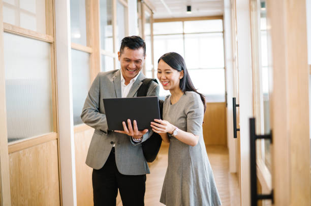istock Two Asian Chinese businesspeople talking in corridor. 1487272294