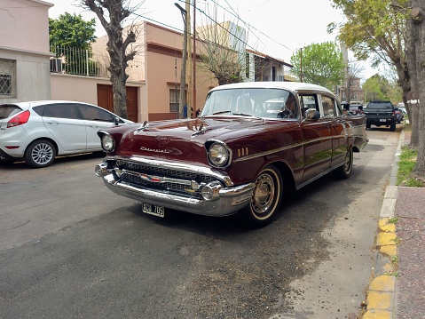 Bernal, Argentina – September 19, 2022: Bernal, Argentina - Sept 18, 2022: Old red burgundy 1957 Chevrolet Chevy Bel Air sport sedan two door parked in the street. Iconic classic car.