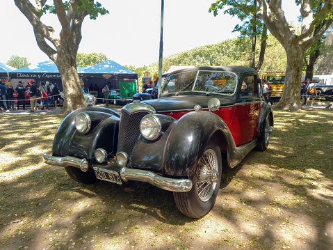 San Isidro, Argentina – October 08, 2022: Vintage black and red 1943 Riley RMB 2.5 in a park. Nature, trees. Autoclasica 2022 classic car show.