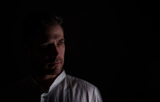 Portrait of confident young man looking at camera posing over black backgorund