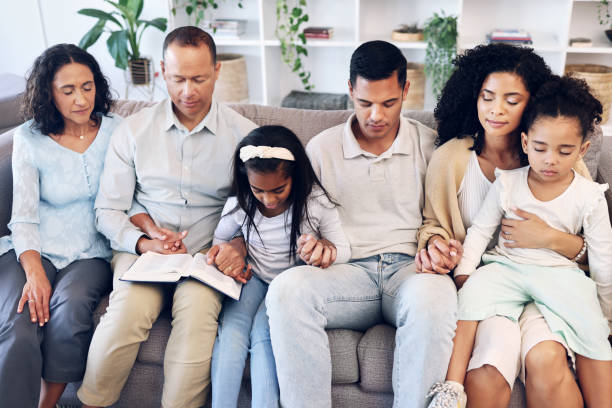 religiosi, religione e famiglia pregano insieme in una casa o in una casa e lodano dio per la pace, la calma e l'anima. gratitudine, spirituale e persone con speranza e pregare per il perdono seduti sul divano o sul divano - 4 of a kind foto e immagini stock