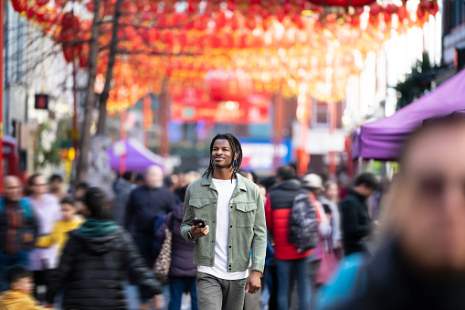 Black mid adult male enjoying a stroll through Londons Chinatown enjoying the colourful hanging Chinese paper lanterns