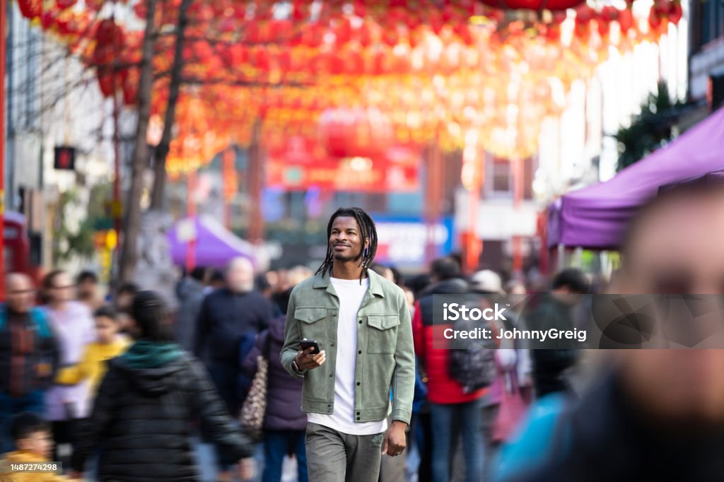 Man in his 30s walking through Soho, London Black mid adult male enjoying a stroll through Londons Chinatown enjoying the colourful hanging Chinese paper lanterns Color Image Stock Photo