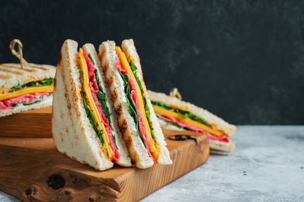 明るいコンクリートの背景にソーセージ、チーズ、ルッコラの自家製サンドイッチ2つ - club sandwich sandwich salad bread ストックフォトと画像