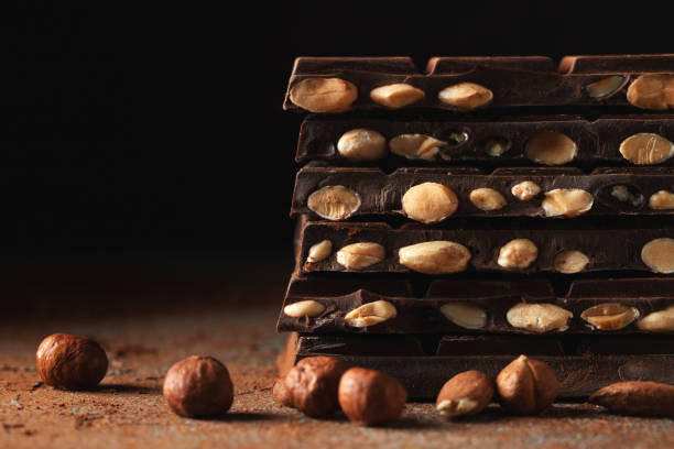 istock Dark and milk chocolate with nuts on a dark background sprinkled with cocoa powder. 1487279122