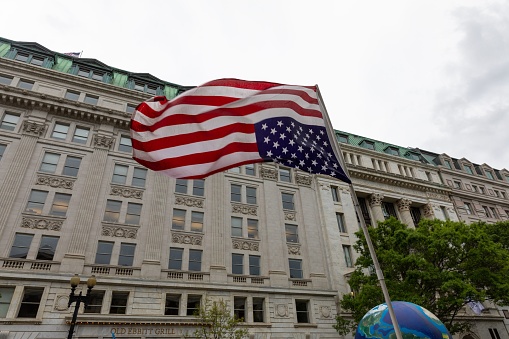 Washington DC, United States – April 23, 2023: An American flag hanging upside down in a windy environment, with the stripes and stars of the national banner fluttering