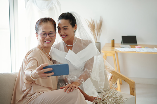 Senior woman taking selfie with daughter on her wedding day