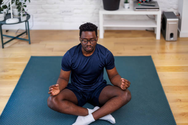istock A young African is sitting on the floor and meditating. 1487282087