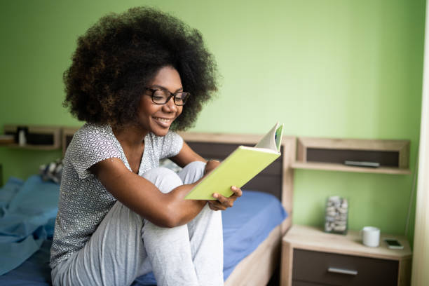 istock Young afro woman reading a book in her bed 1487285613