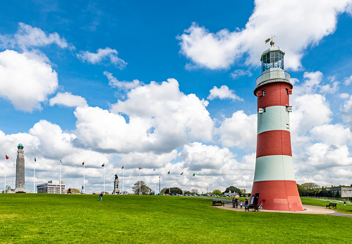 Plymouth, UK. 2 April 2023. People sitting on 'The Hoe' public park at Smeaton's Lighthouse Tower in Plymouth