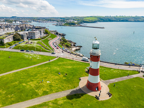 Plymouth, UK. 2 April 2023. People sitting on 'The Hoe' public park at Smeaton's Lighthouse Tower in Plymouth