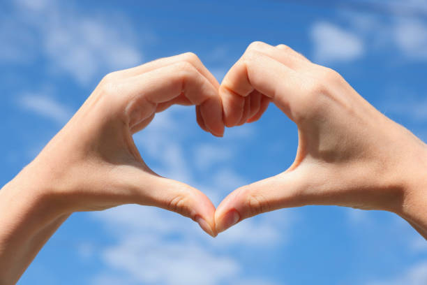 istock Woman making heart with hands against blue sky, closeup 1487290064