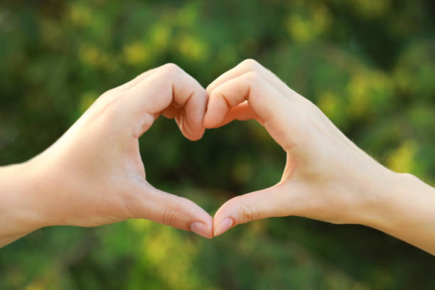 istock Couple making heart with hands outdoors on sunny day, closeup 1487290086