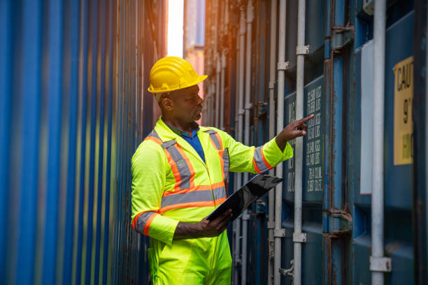 Male Industrial Engineer in White Hard Hat checking container at container yard warehouse. Logistics business. stock photo