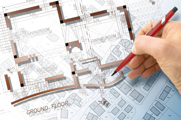istock Architect drawing a residential building project over an imaginary cadastral map of territory with buildings and land plots 1487292006