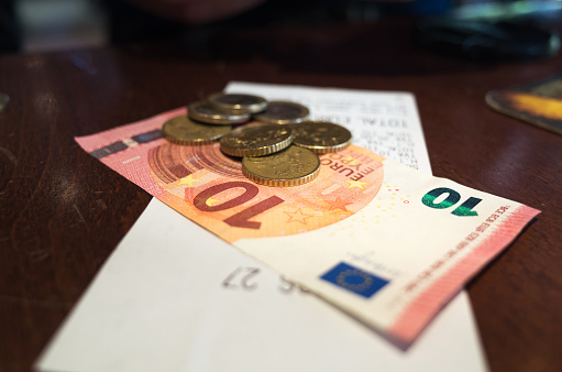Paying the bill in Euros, coins and notes, at a cafe.
