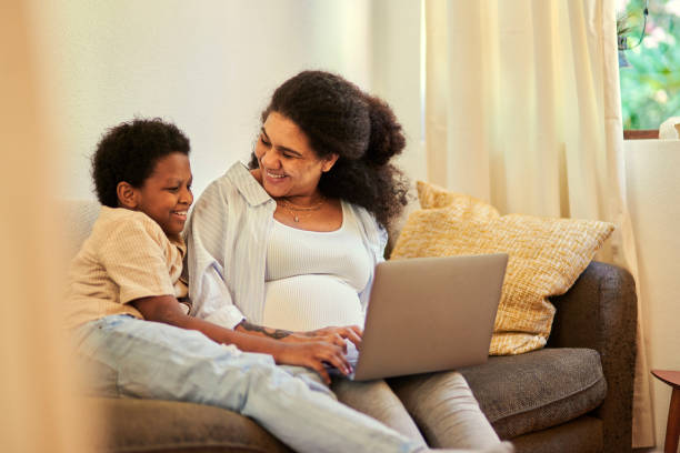 istock Laptop, happy and mom with her kid on a sofa relaxing while browsing on social media. Conversation, bonding and pregnant woman sitting with a boy child doing research with computer in living room. 1487293393