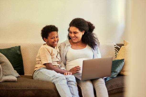 istock Laptop, conversation and mother with her child on a sofa relaxing while browsing on social media. Happy, bonding and pregnant woman sitting with a boy kid doing research with computer in living room. 1487293403