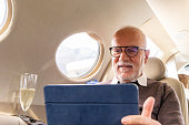 Senior business man working on digital tablet in a private jet