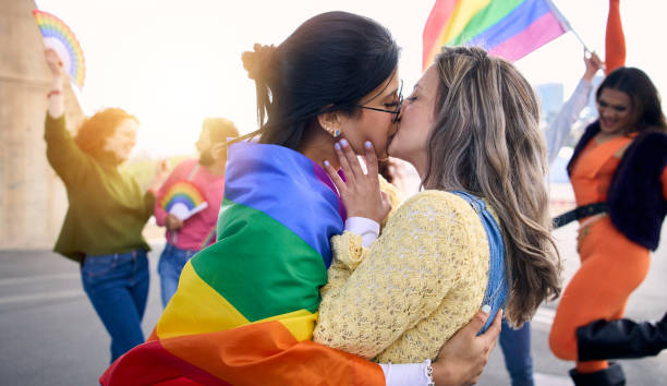Two young loving girls kissing on gay pride festival day outdoors. Generation z types of sexuality. stock photo
