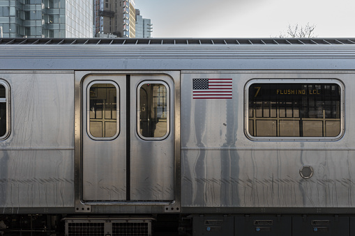 Side of classic New York subway car with highrises behind on cold and clear day in Brooklyn