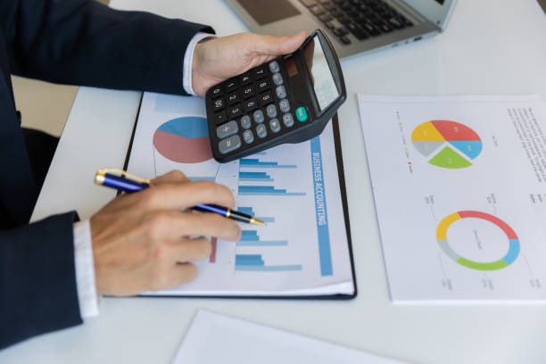istock Asian businessman working at office with laptop, tablet and graph data sheet on his desk. 1487296078