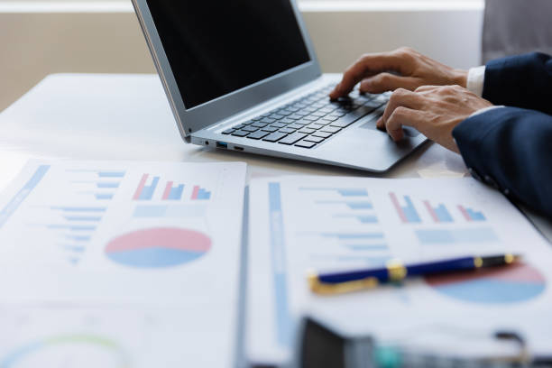 istock Asian businessman working at office with laptop, tablet and graph data sheet on his desk. 1487296079