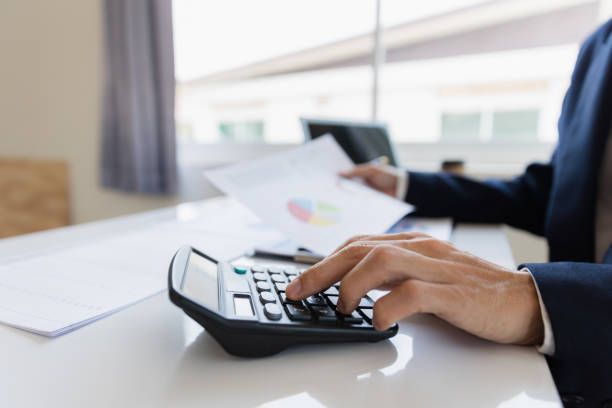 istock Asian businessman working at office with laptop, tablet and graph data sheet on his desk. 1487296087