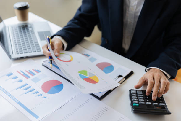 istock Asian businessman working at office with laptop, tablet and graph data sheet on his desk. 1487296094