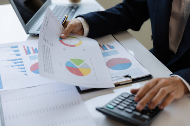 istock Asian businessman working at office with laptop, tablet and graph data sheet on his desk. 1487296103