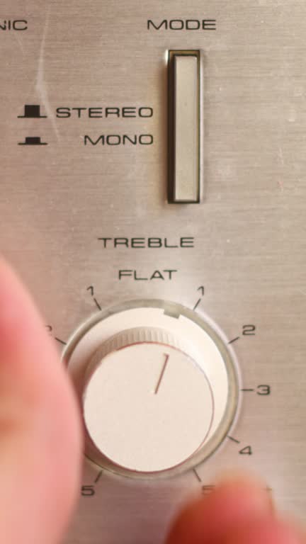 Close up of hand turning a volume knob on home stereo unit. Vertical video for social media.