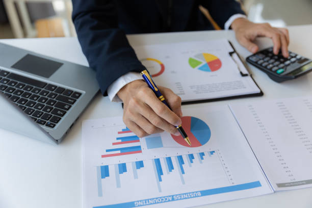 istock Asian businessman working at office with laptop, tablet and graph data sheet on his desk. 1487296812