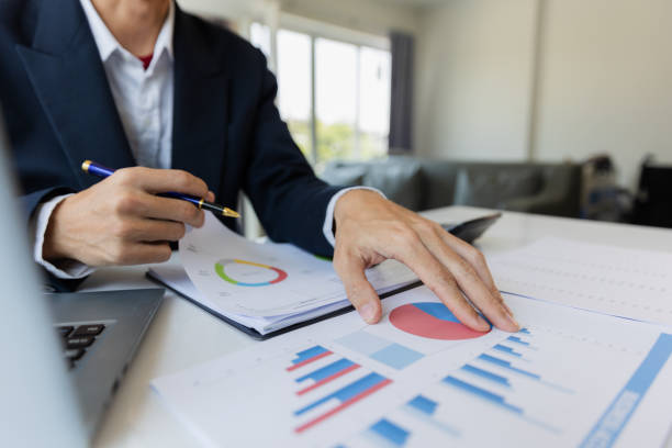istock Asian businessman working at office with laptop, tablet and graph data sheet on his desk. 1487297055