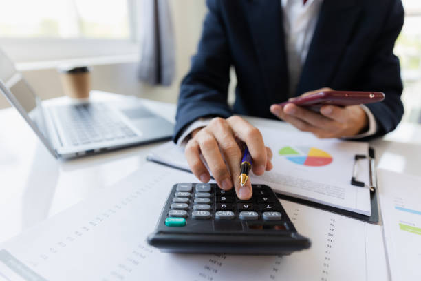 istock Asian businessman working at office with laptop, tablet and graph data sheet on his desk. 1487297062