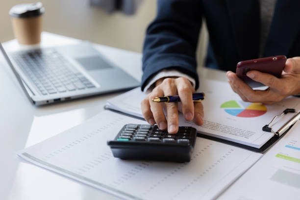 istock Asian businessman working at office with laptop, tablet and graph data sheet on his desk. 1487297119