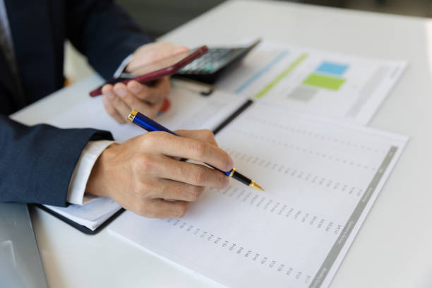 istock Asian businessman working at office with laptop, tablet and graph data sheet on his desk. 1487297157