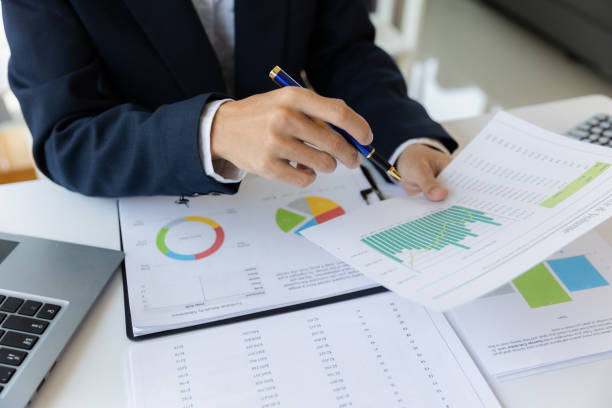 istock Asian businessman working at office with laptop, tablet and graph data sheet on his desk. 1487297189