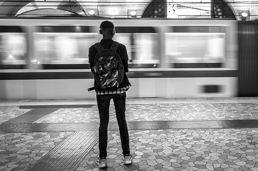 Rome, Italy, October 16 -- A young adult waits for the train in a Metro station in the historic center of Rome. Composed of three lines for a total of 54 km and 73 stops, 60 of which underground, the Rome subway network is the second largest in Italy, after the Milan underground in the north of the country. Wide angle image in high definition quality.