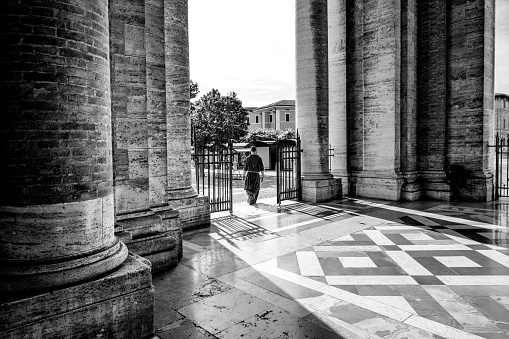 Assisi, Umbria, Italy, August 30 -- A typical scene of daily life in Assisi with a Franciscan friar walking under the colonnade of the Basilica di Santa Maria degli Angeli, in the Assisi municipality, in Umbria. Image in high definition quality.