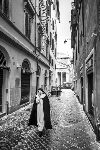 Rome, Italy, March 09 -- A typical scene of daily life in Rome with a Catholic nun walking along the alleys of the Pantheon district, in the historic heart of the Eternal City. In 1980 the historic center of Rome was declared a World Heritage Site by Unesco. Image in high definition quality.