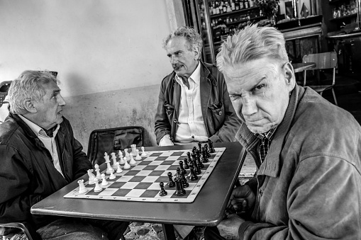 Rome, Italy, May 21 -- An adult man makes a silly face during a game of chess with his friends outside a café in the Piazza Navona district, in the historic heart of Rome. Super wide angle image in high definition quality.