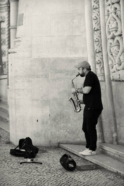 Lisbon, Portugal - December 17, 2022: A street musician plays a saxophone at the entrance of the Rossio Rail Station in Lisbon downtown.