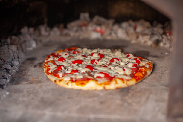 istock Cooking real pizza in a brick oven. Wood and fire are burning 1487300413