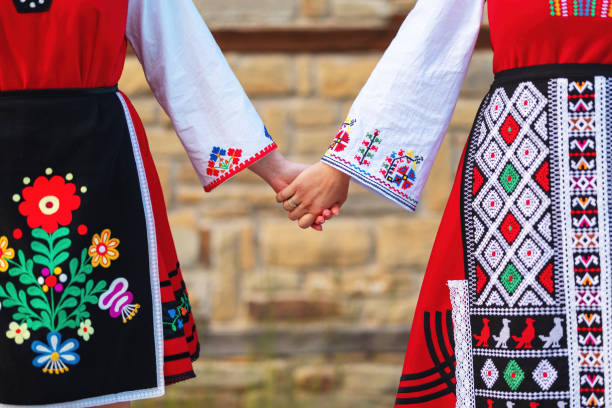 meninas em trajes étnicos tradicionais búlgaros com bordados folclóricos de mãos dadas. o espírito da bulgária - cultura, história e tradições. - needlecraft product fotos - fotografias e filmes do acervo