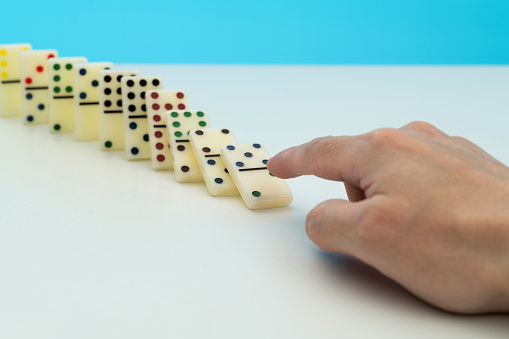Human finger pushing domino pieces